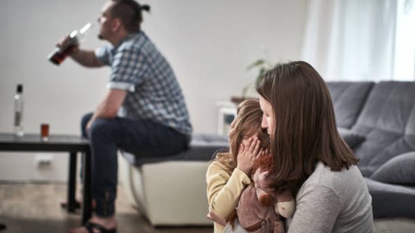 otac alkoholičar pije alkohol iz boce, uplašeno dijete